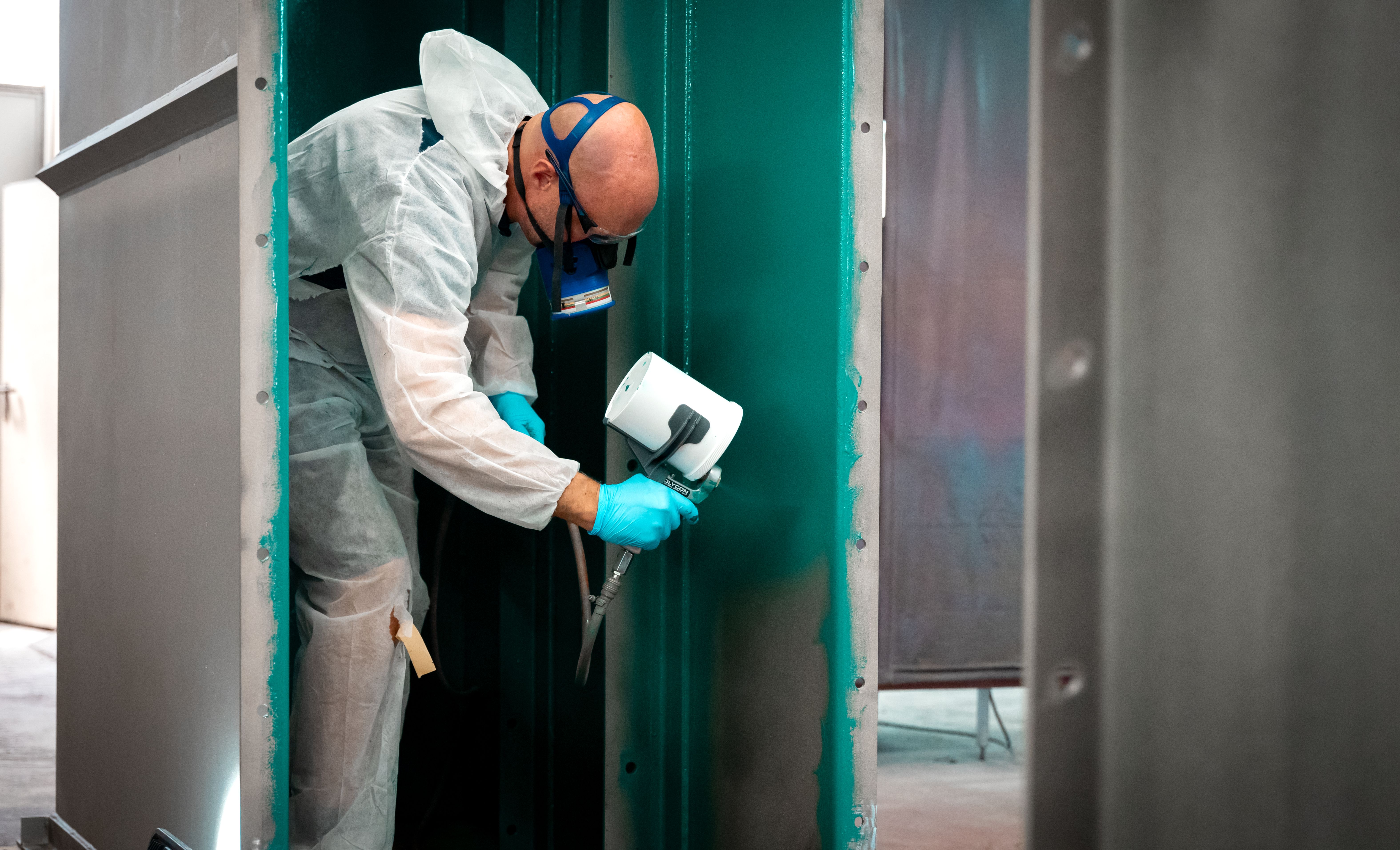 Un bărbat cu mască pulverizează un strat verde de control